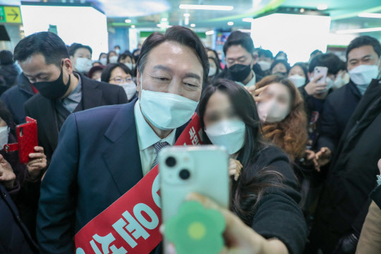 윤석열 국민의힘 대선 후보가 14일 오후 부산 도시철도 서면역에서 퇴근길 시민들과 인사하며 셀카를 찍고 있다.    [국민의힘 선대위 제공]